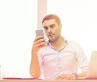 man looking at mobile app and writing business plan